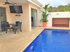 Pool area with seating and gas BBQ grill as seen at night with LED lights